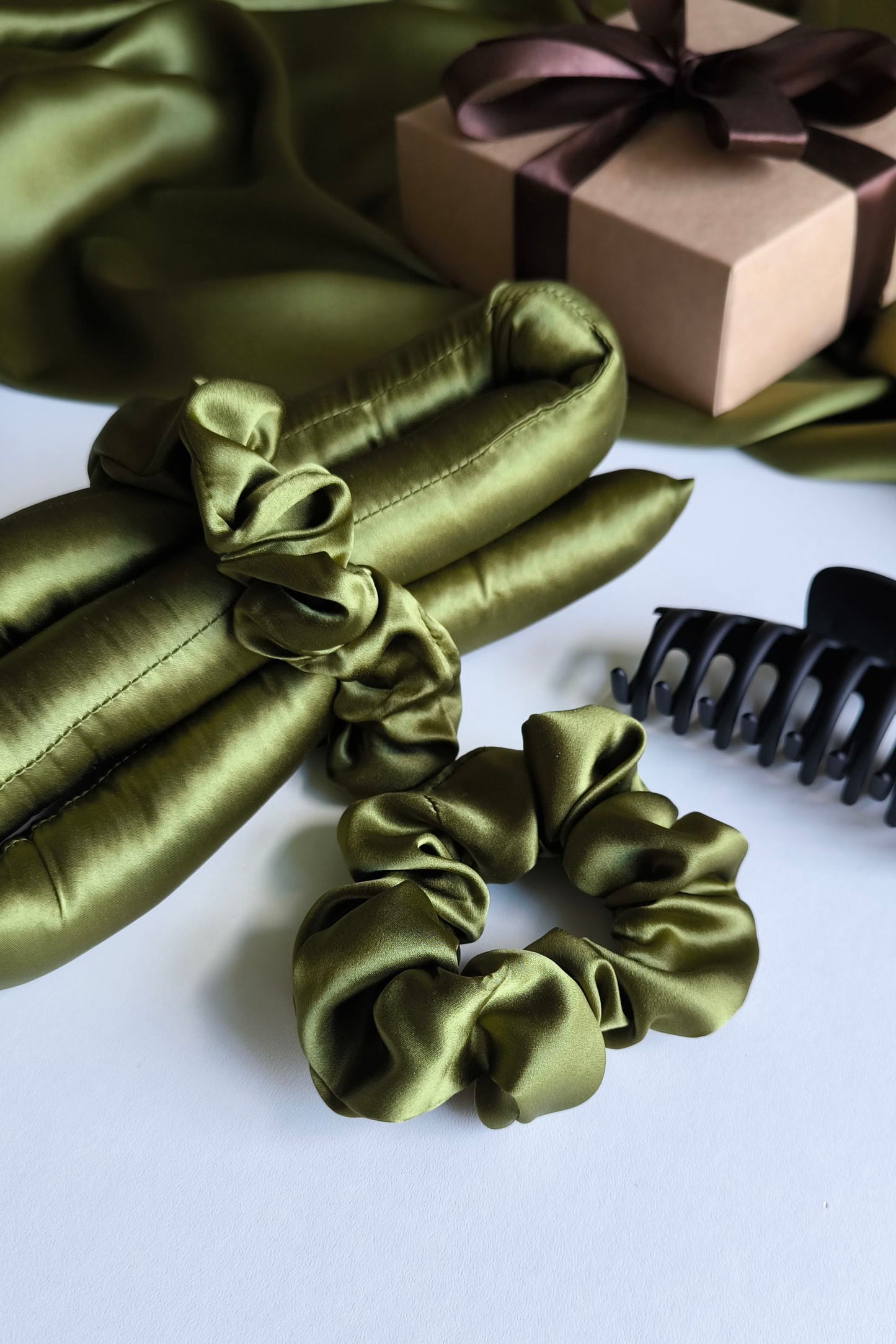 Green satin hair accessories including scrunchies and a bow, with a gift box in the background.