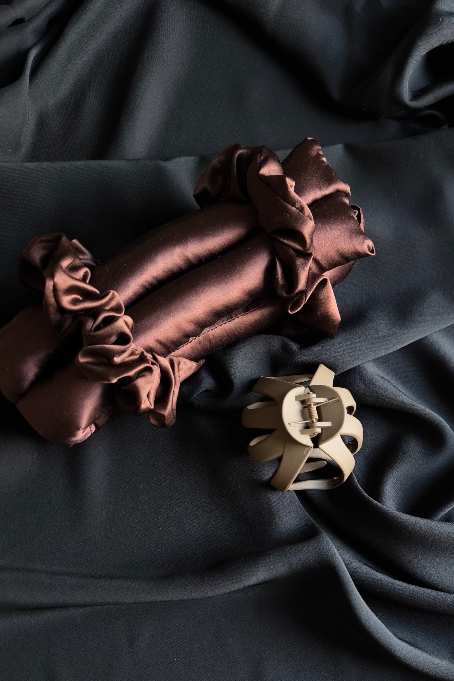 Brown satin fabric with decorative hair clip on a black background
