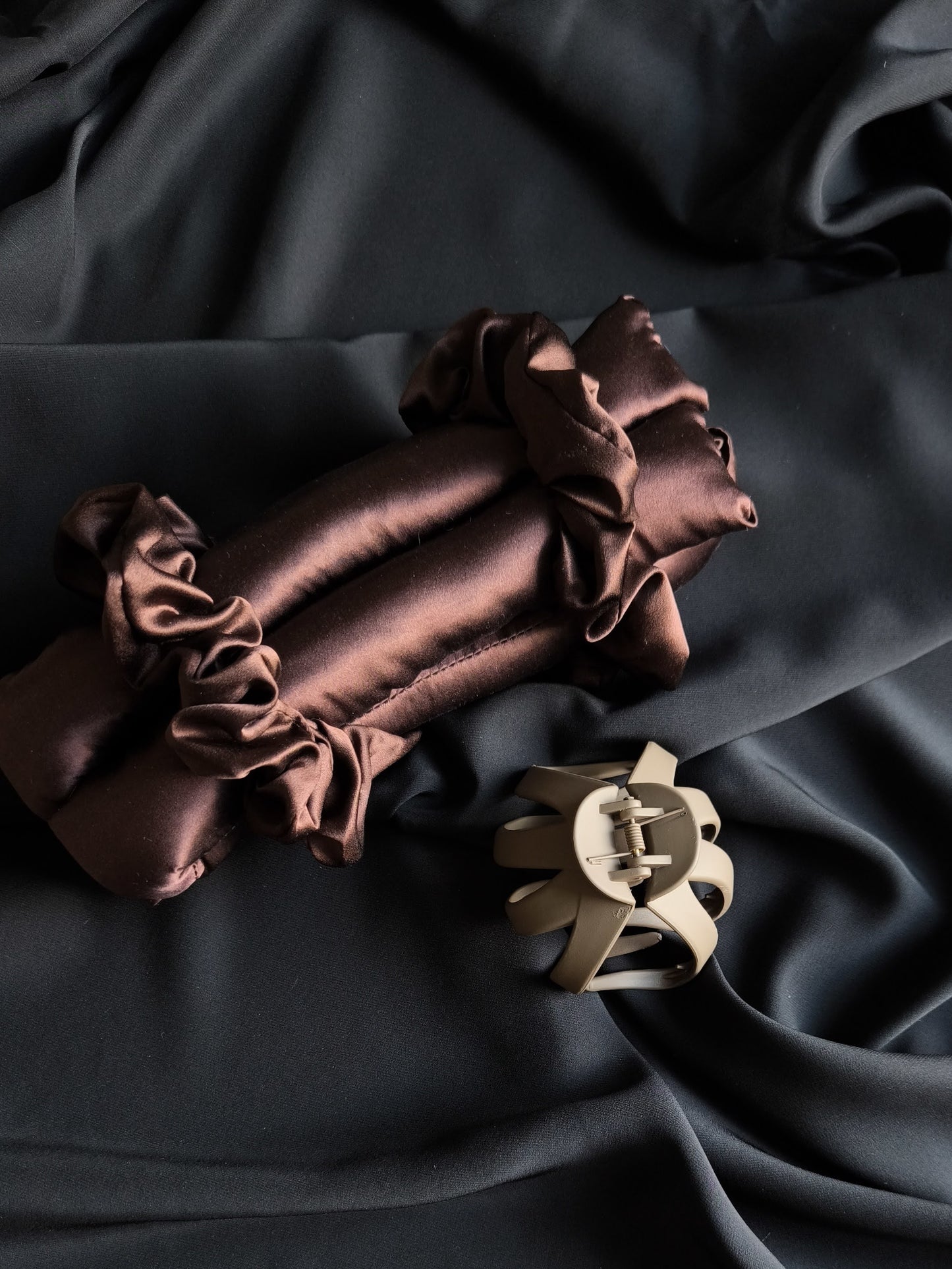 Brown satin fabric with a decorative clip on a dark background