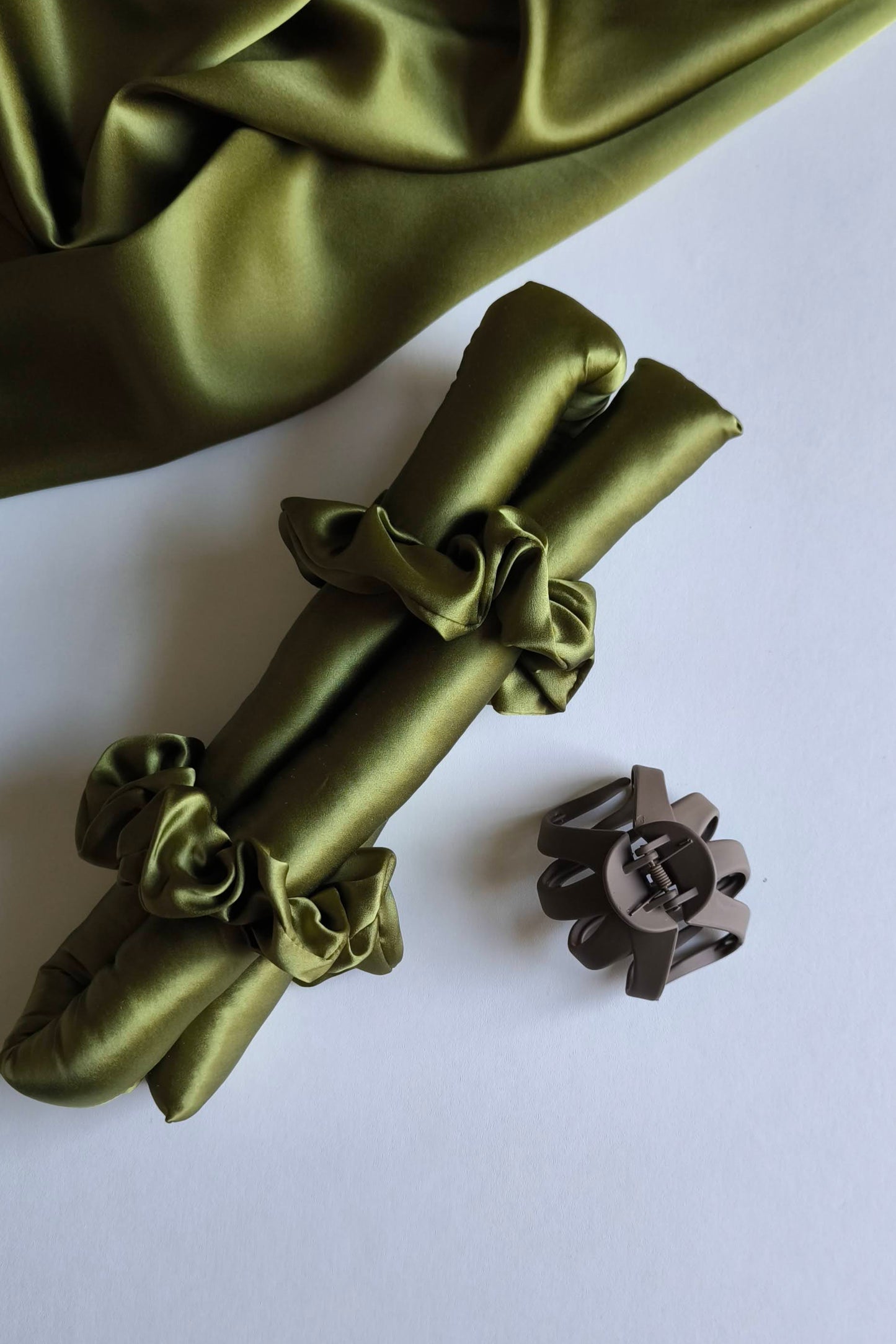 Green satin hair accessories and a hair clip on a white background