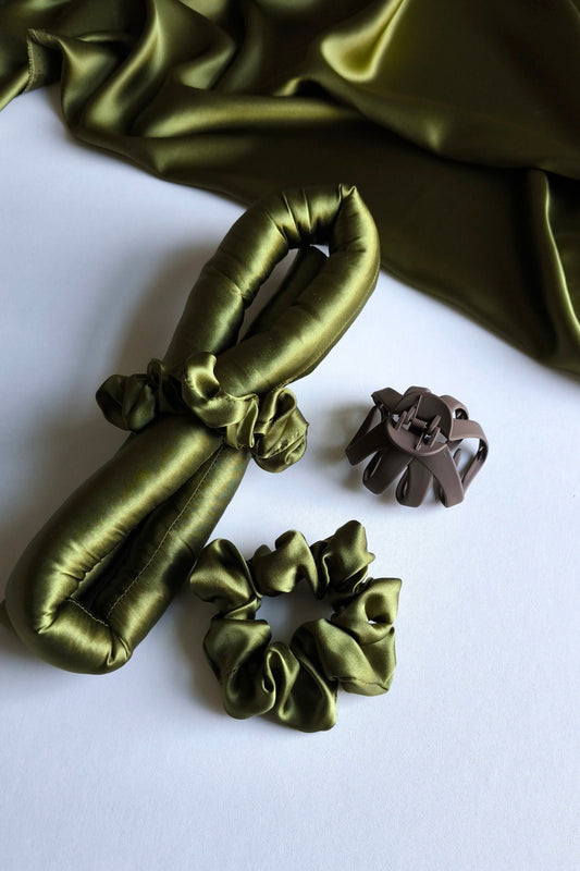 Green satin scrunchies on a white surface with green fabric in the background
