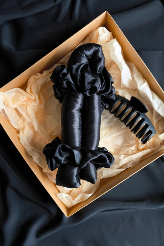 Black hair accessories in a box on a black fabric background