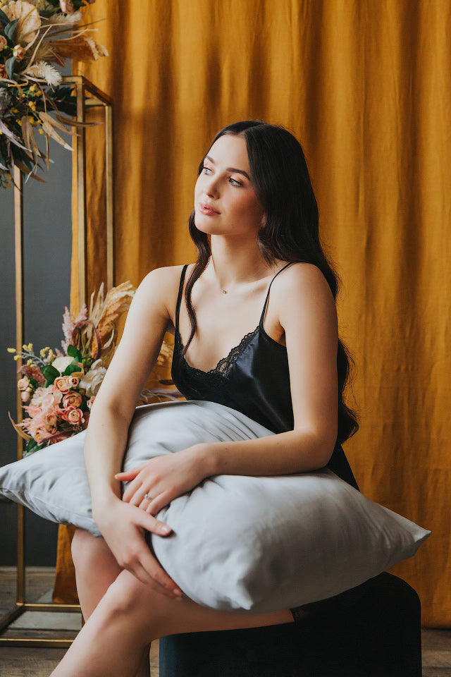 spilvens ar zīda spilvendranu, sieviete tur klēpī