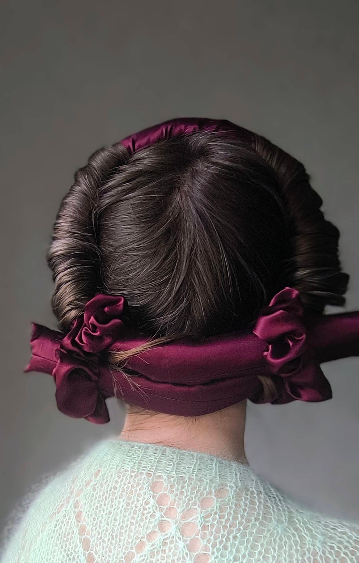 Person wearing a silk hair curler on a plain background