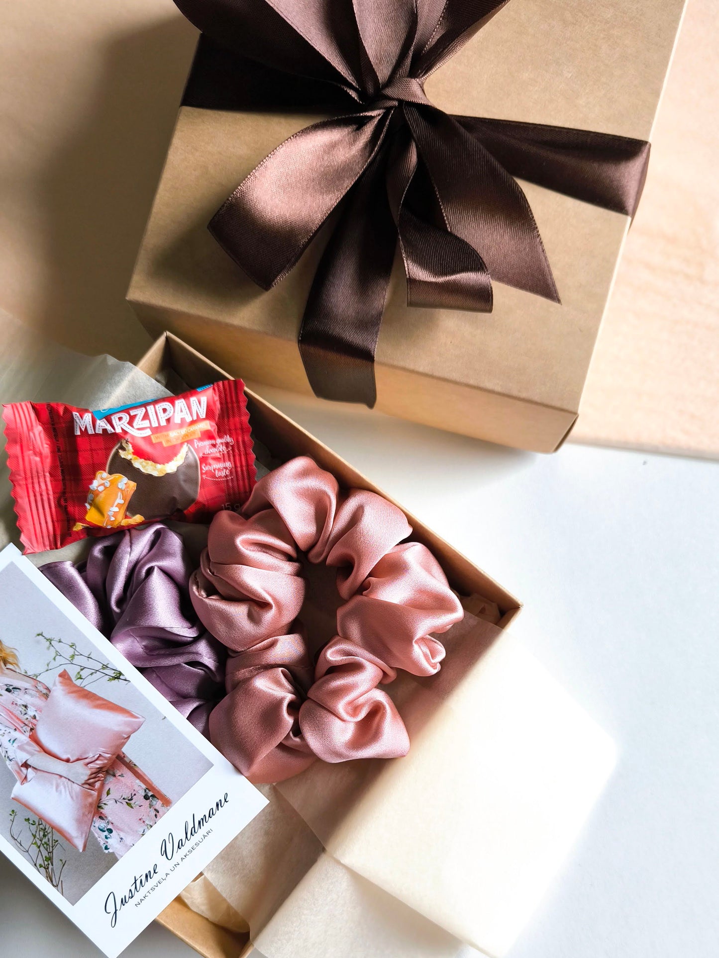 Gift box with scrunchies and a chocolate bar on a light background