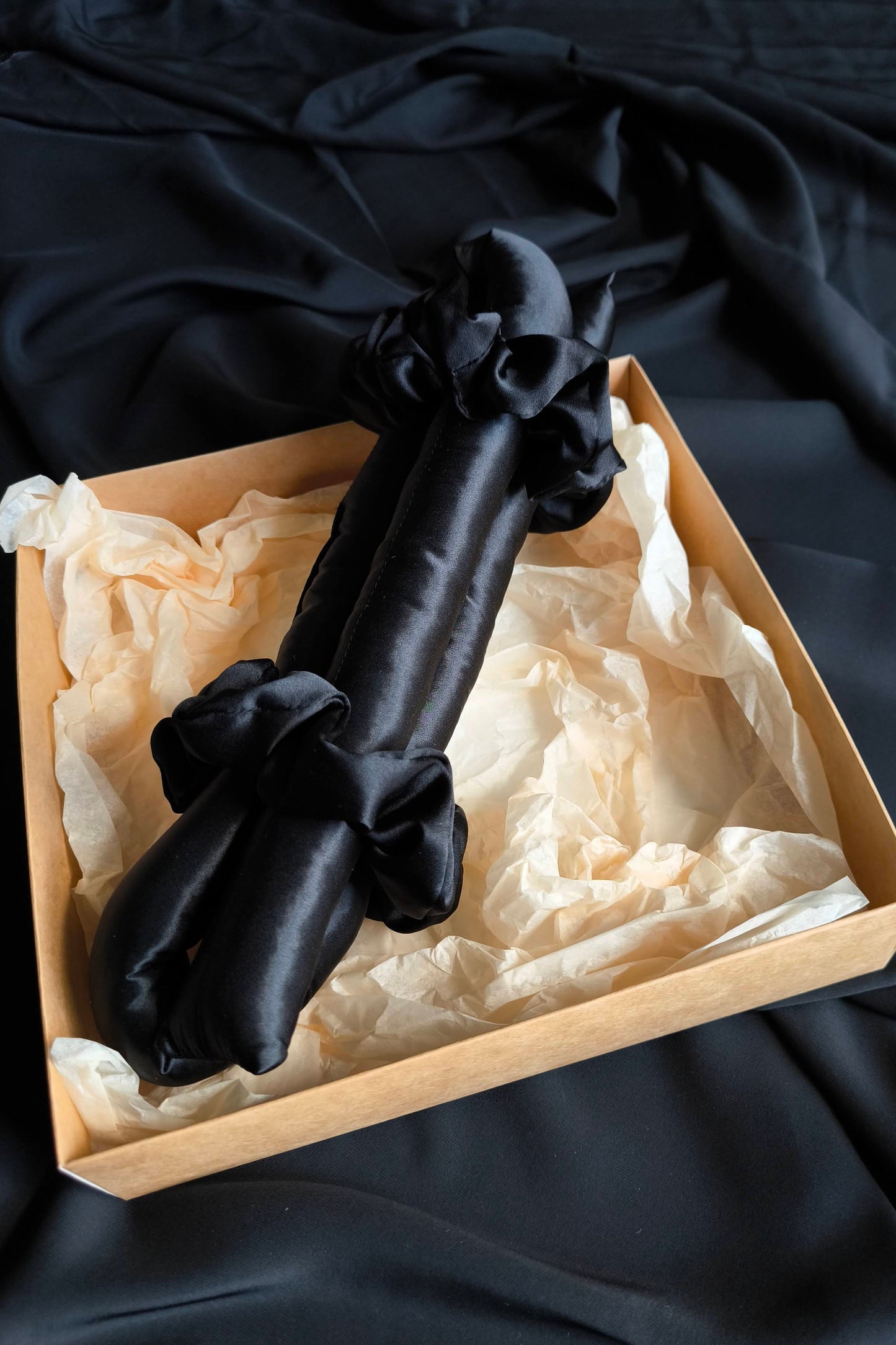 Black heatless hair curler in a box on a dark fabric background