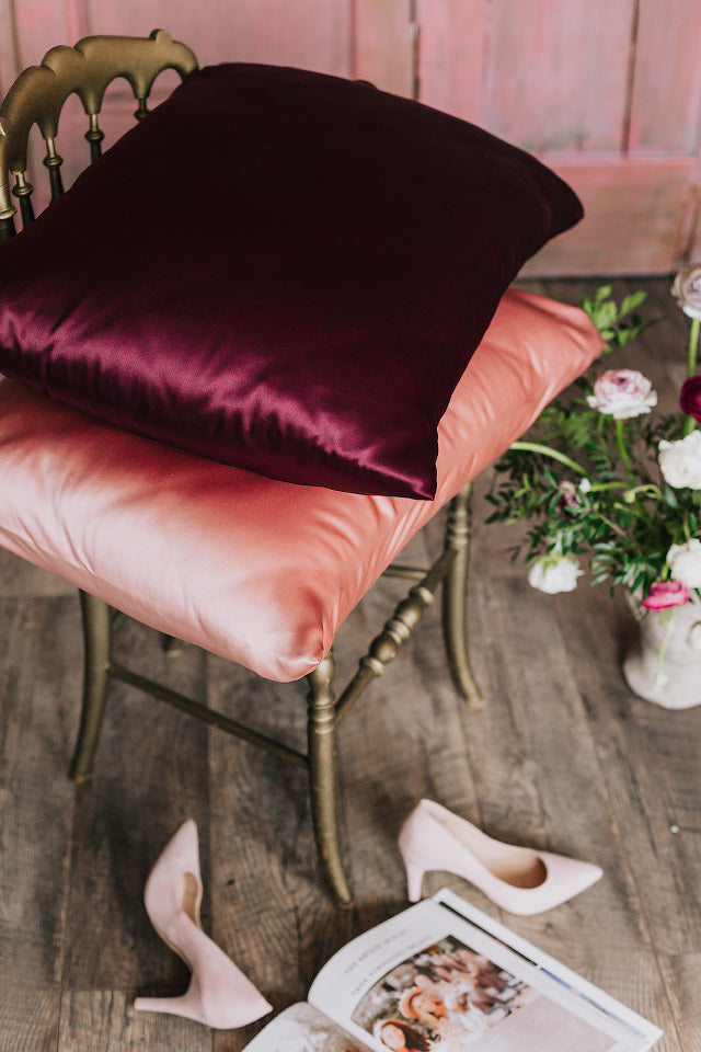 divi spilveni uz rēsla ar zīda spilvendrānām, rozā un bordo krāsā, sāna skats