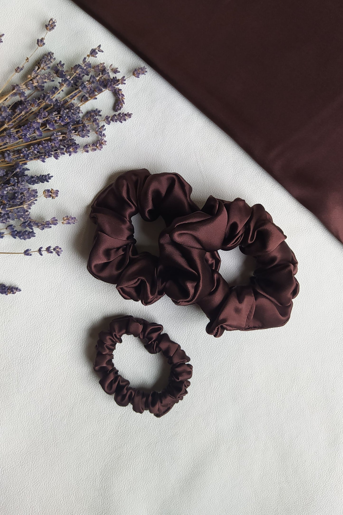 Brūnas dabīgā zīda 3 matu gumijas, S un M izmērs, uz galda