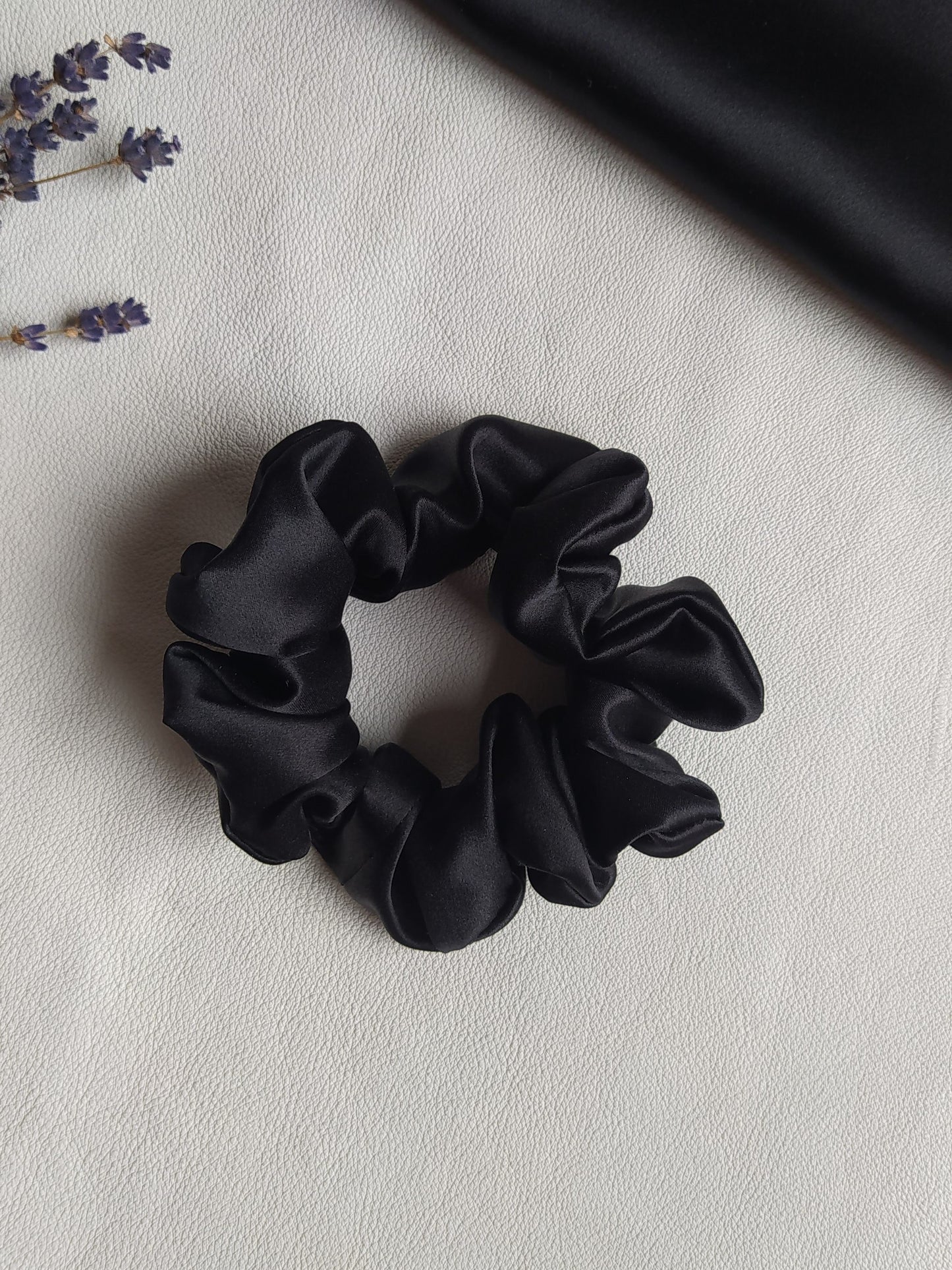 Melna dabīgā zīda matu gumija, M izmērs, uz galda