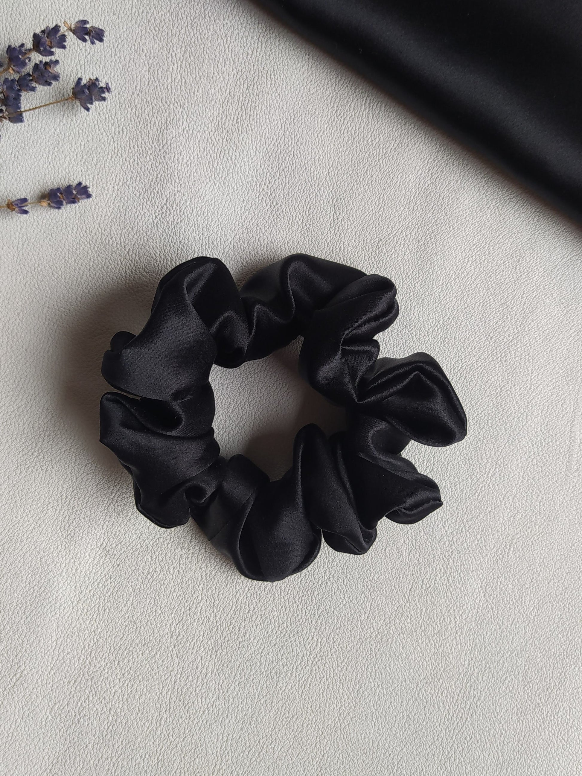 Melna dabīgā zīda matu gumija, M izmērs, uz galda