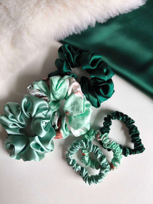 Green and green floral scrunchies on a white surface with green fabric in the background