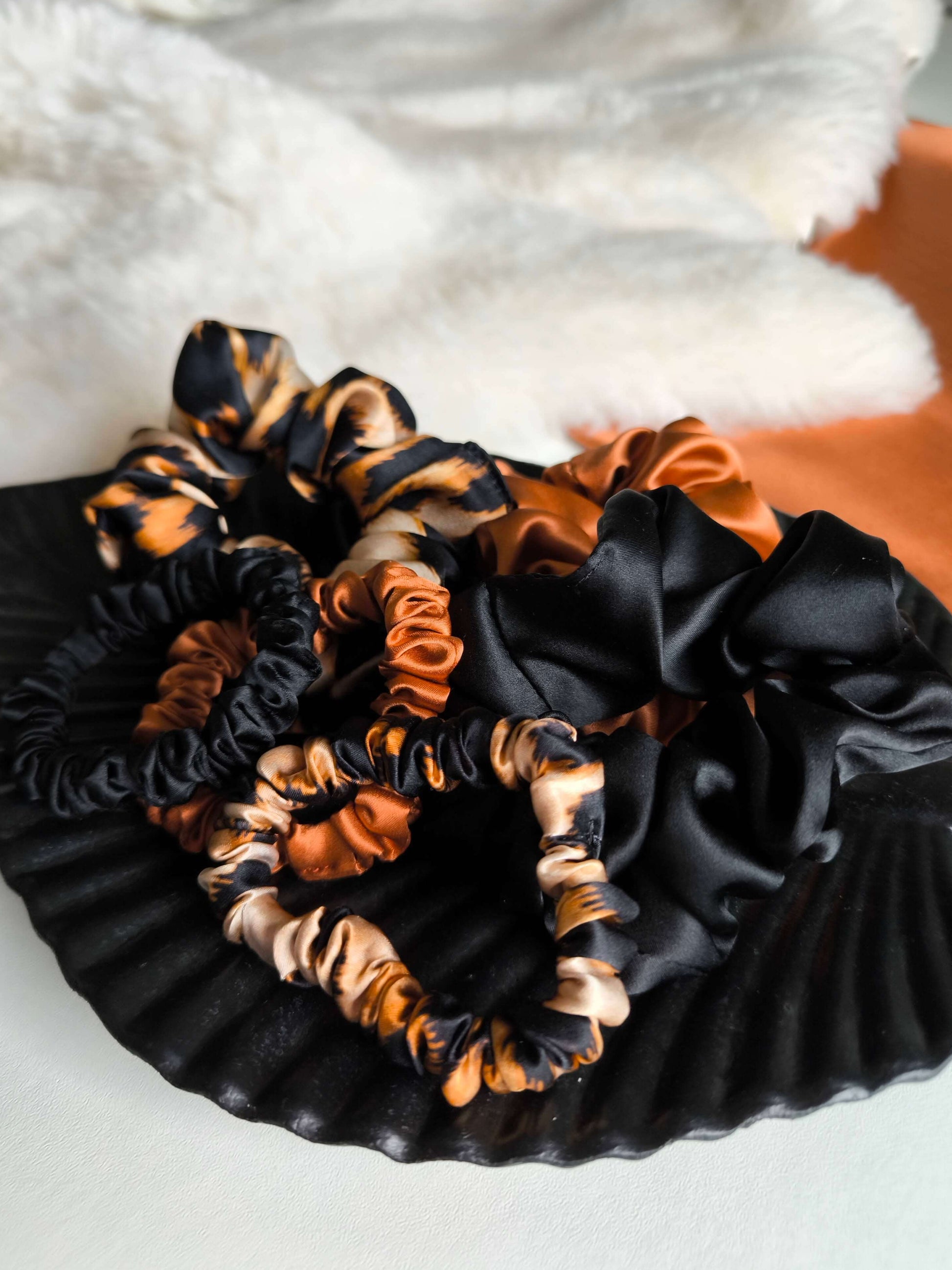 Black and orange scrunchies on a textured white surface