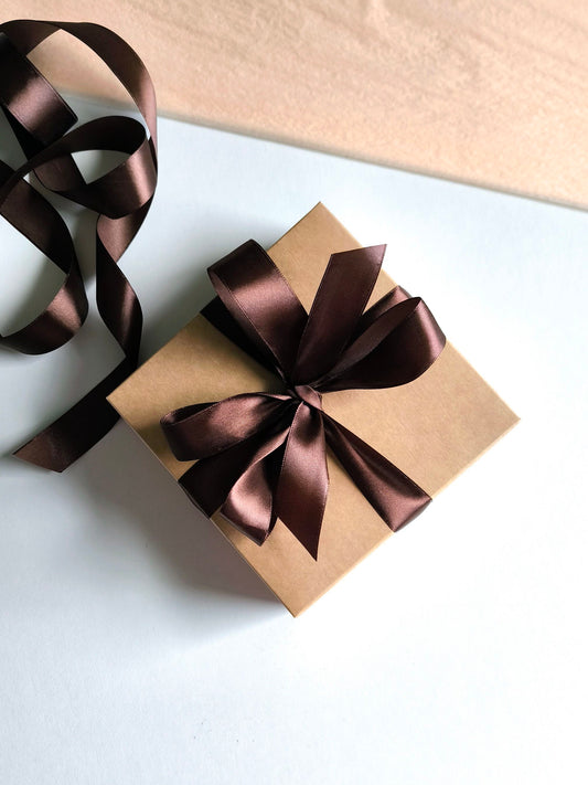 Gift box with brown ribbon on a white surface