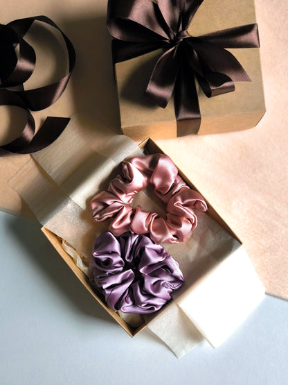 Two satin scrunchies in a gift box with ribbons on a light background