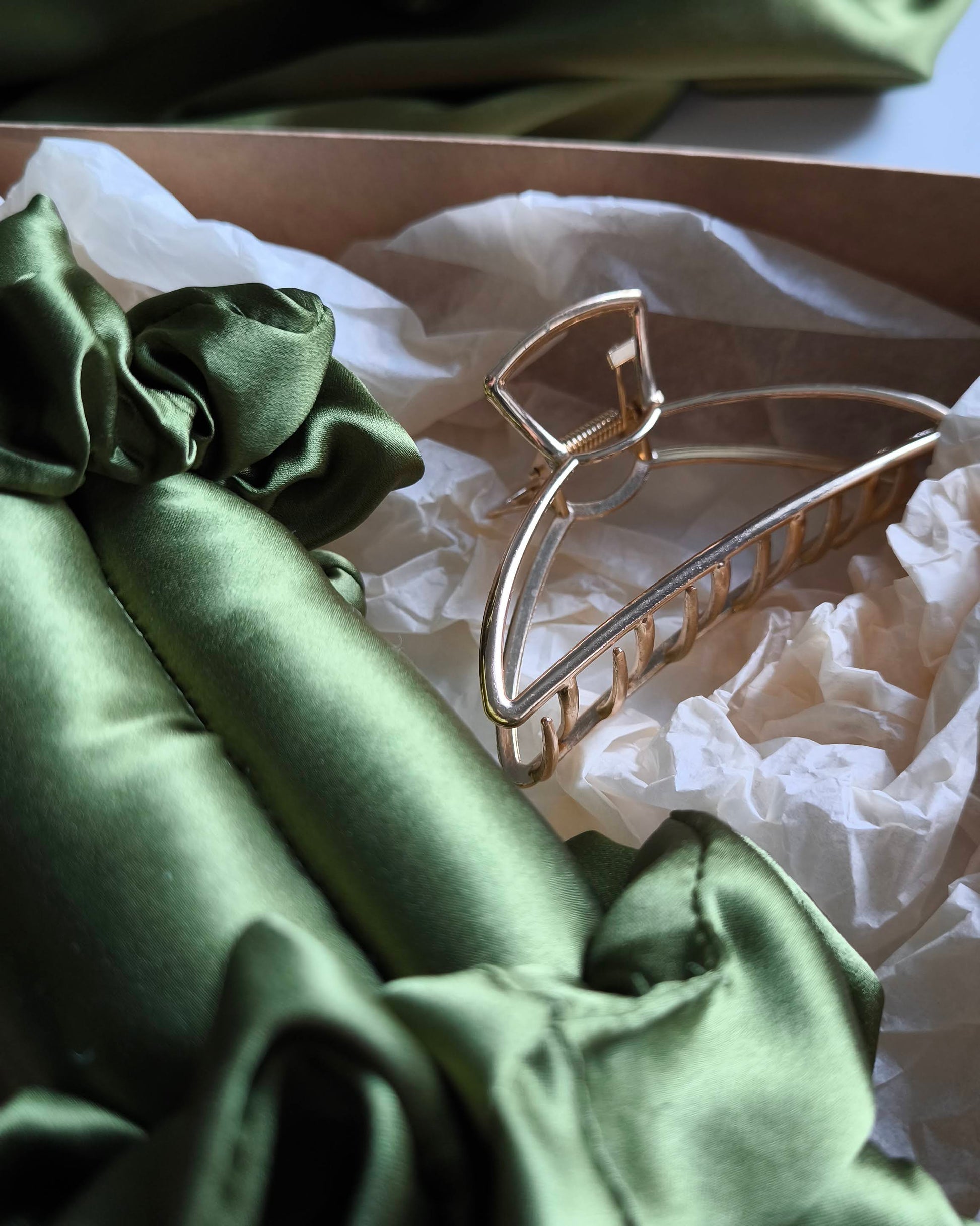 Green satin fabric with a gold hair clip on a white lace background