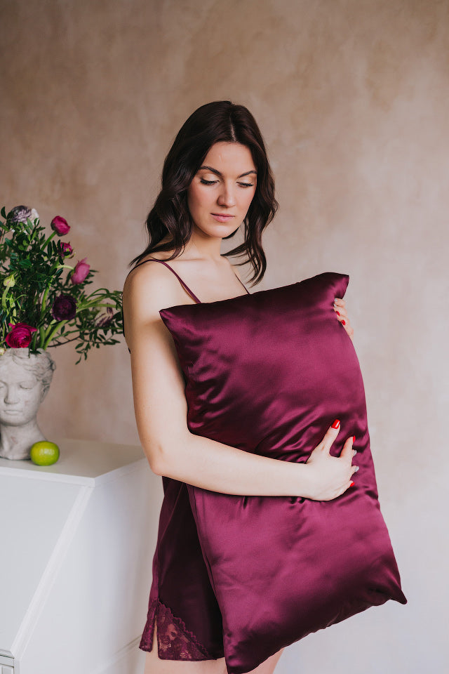 women standing by table holding pillow with bordeoux silk pillowcase