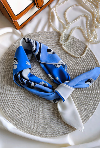 Blue patterned headband on a textured surface with a mirror and pearls in the background