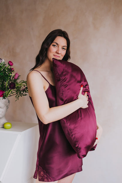 women standing by table holding pillow with bordeoux silk pillowcase by her face