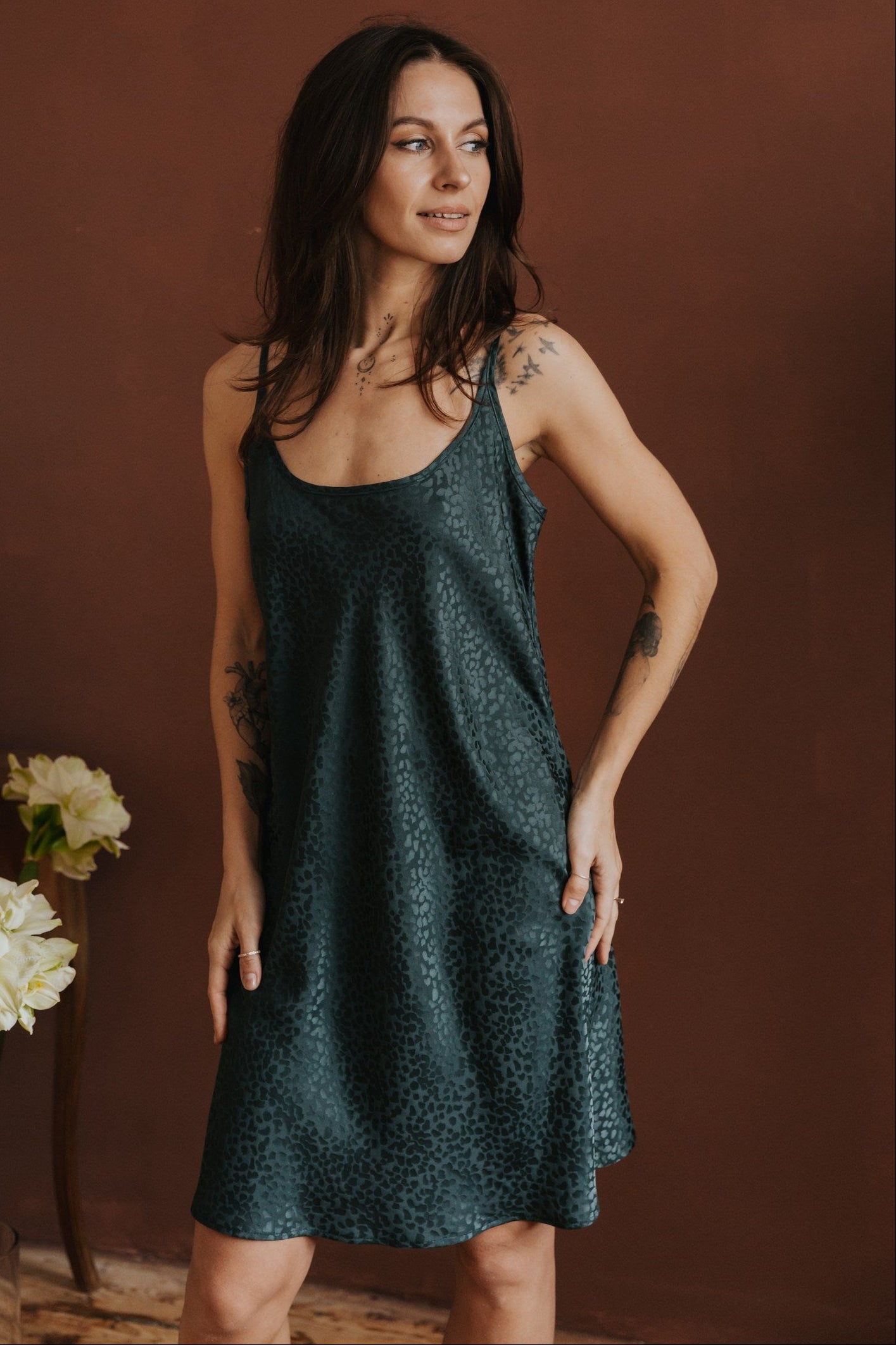 Woman wearing a dark green dress against a brown background