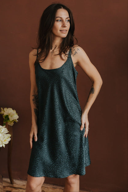 Woman wearing a dark green dress against a brown background