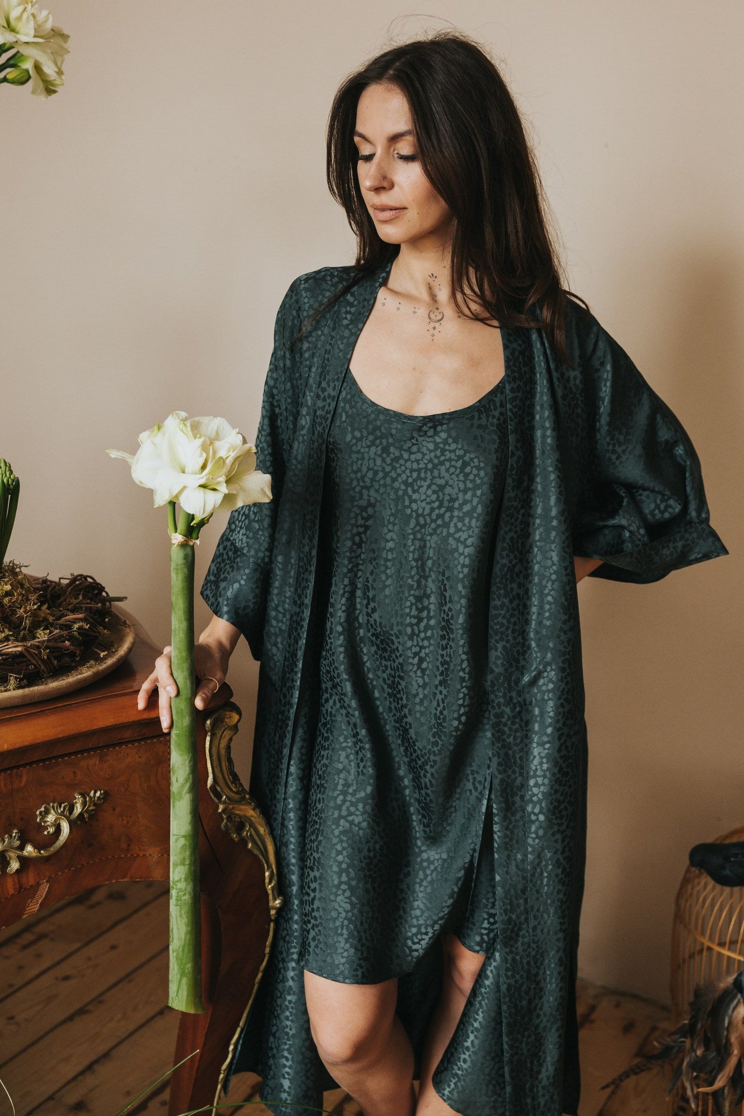 Woman in a green dress holding a flower arrangement indoors.