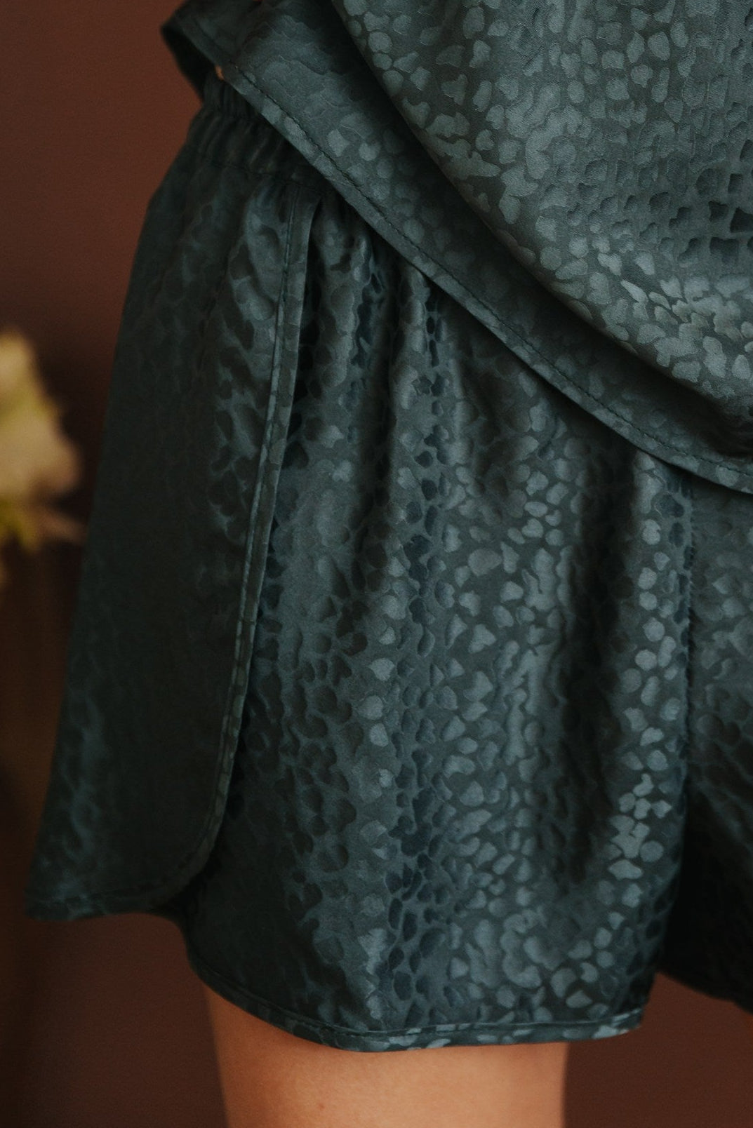 Person wearing a dark green patterned outfit with shorts and a top.