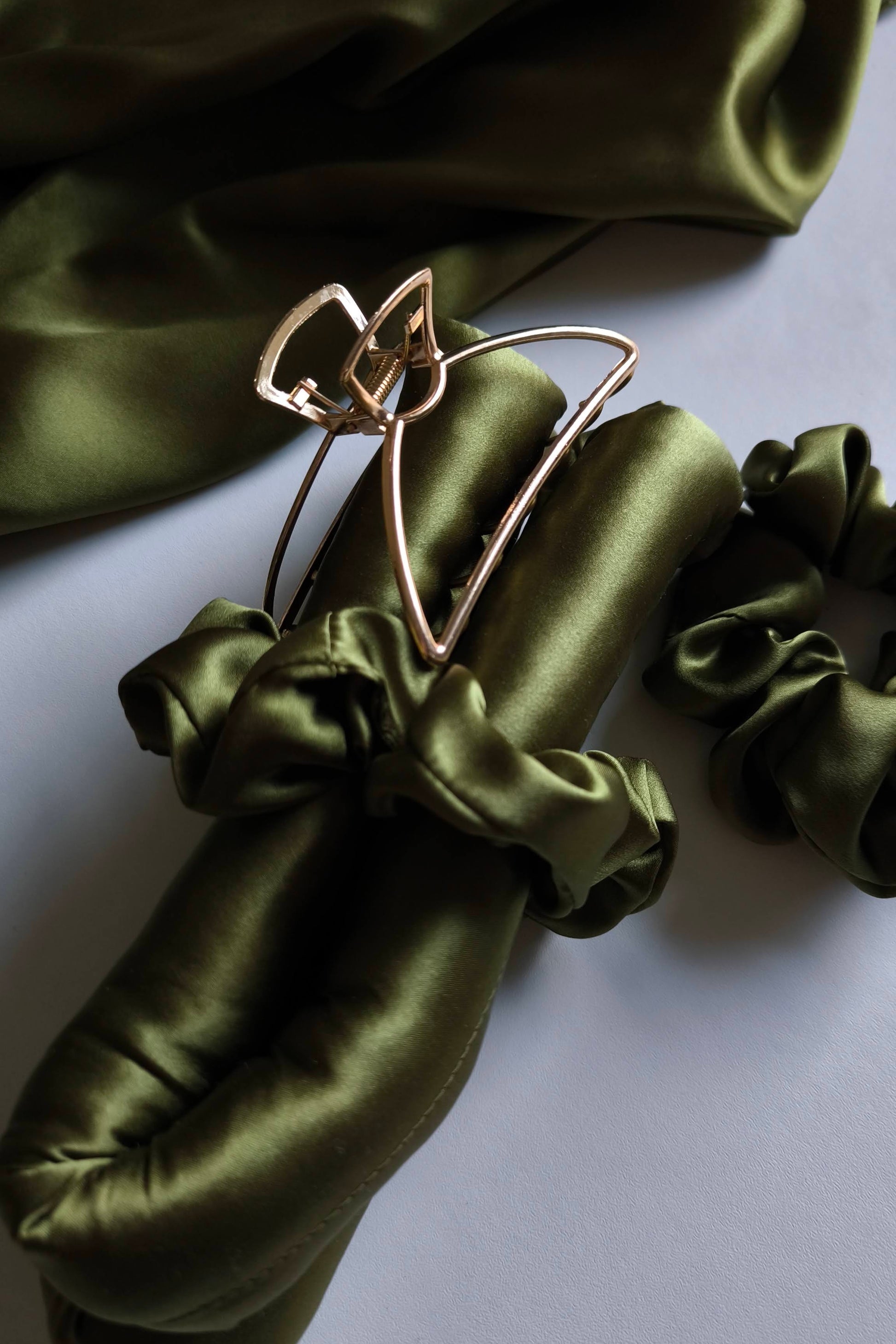 Green satin hair scrunchies with a clip on a white background