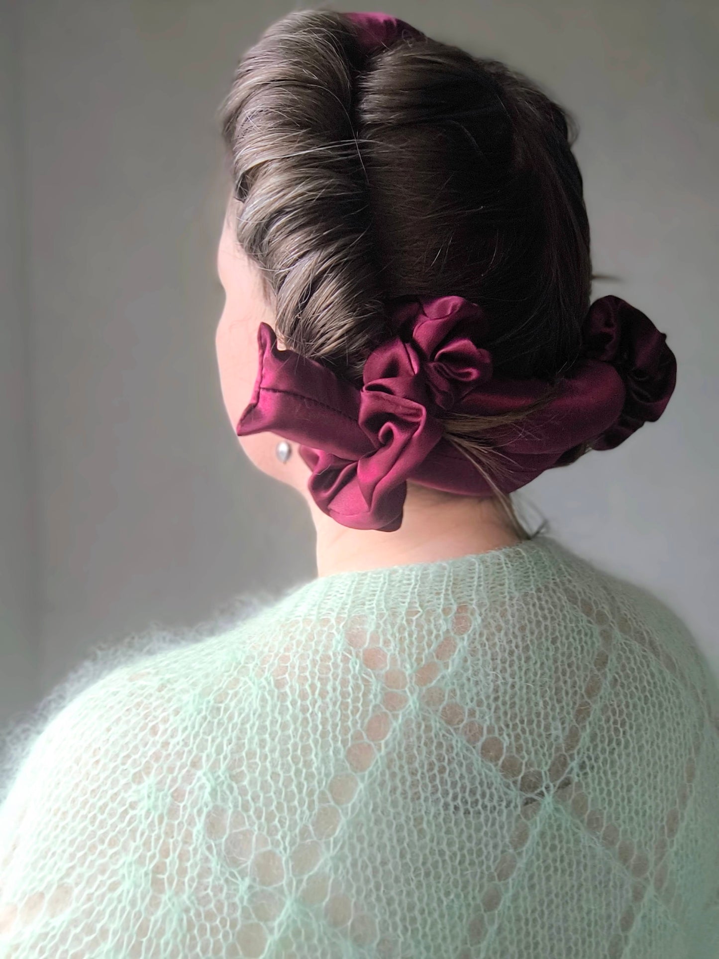 Person with a stylish hair curler with scrunchies against a plain background