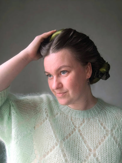 Woman with a bun and green sweater against a gray background