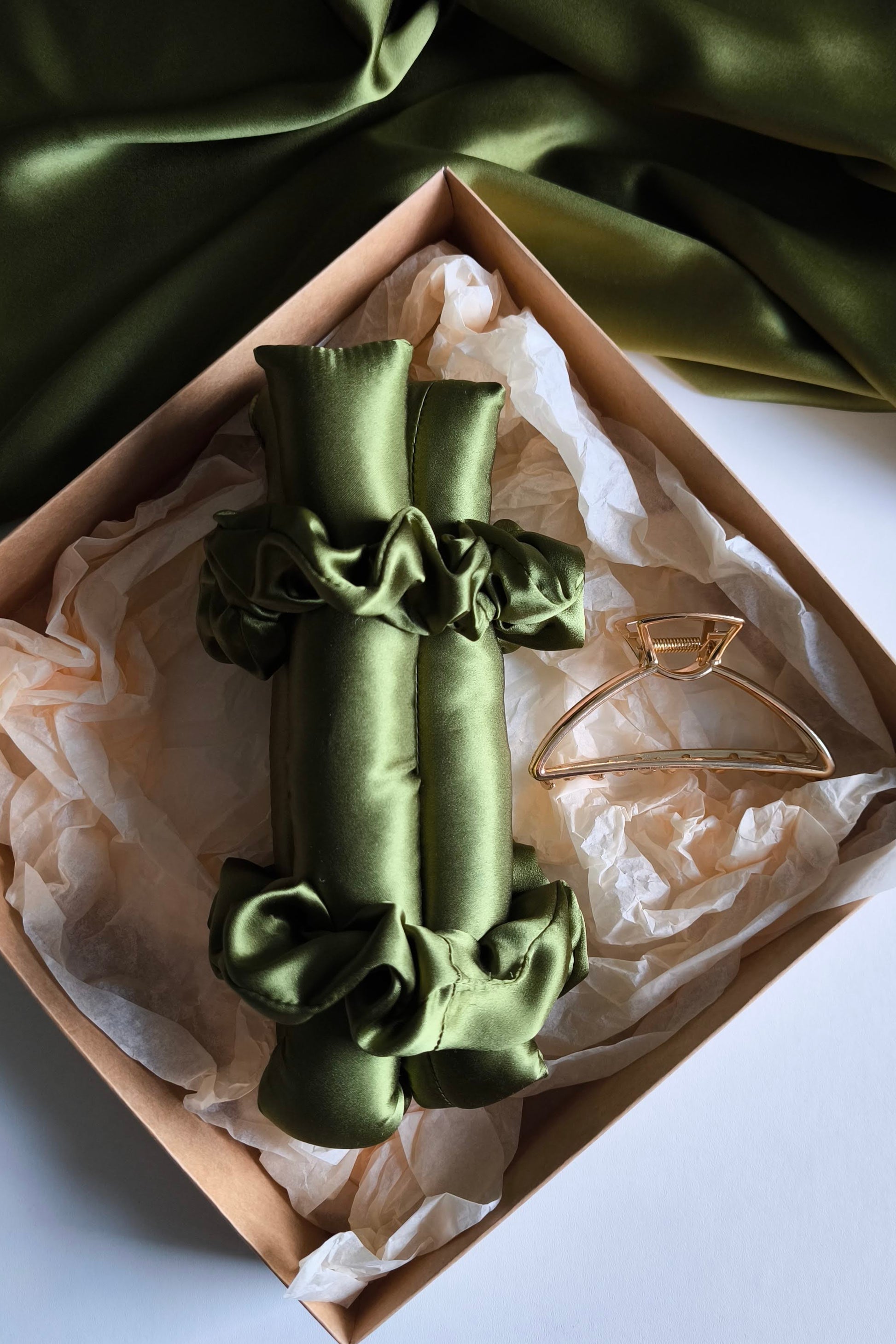 Green satin bow in a decorative box with green fabric in the background