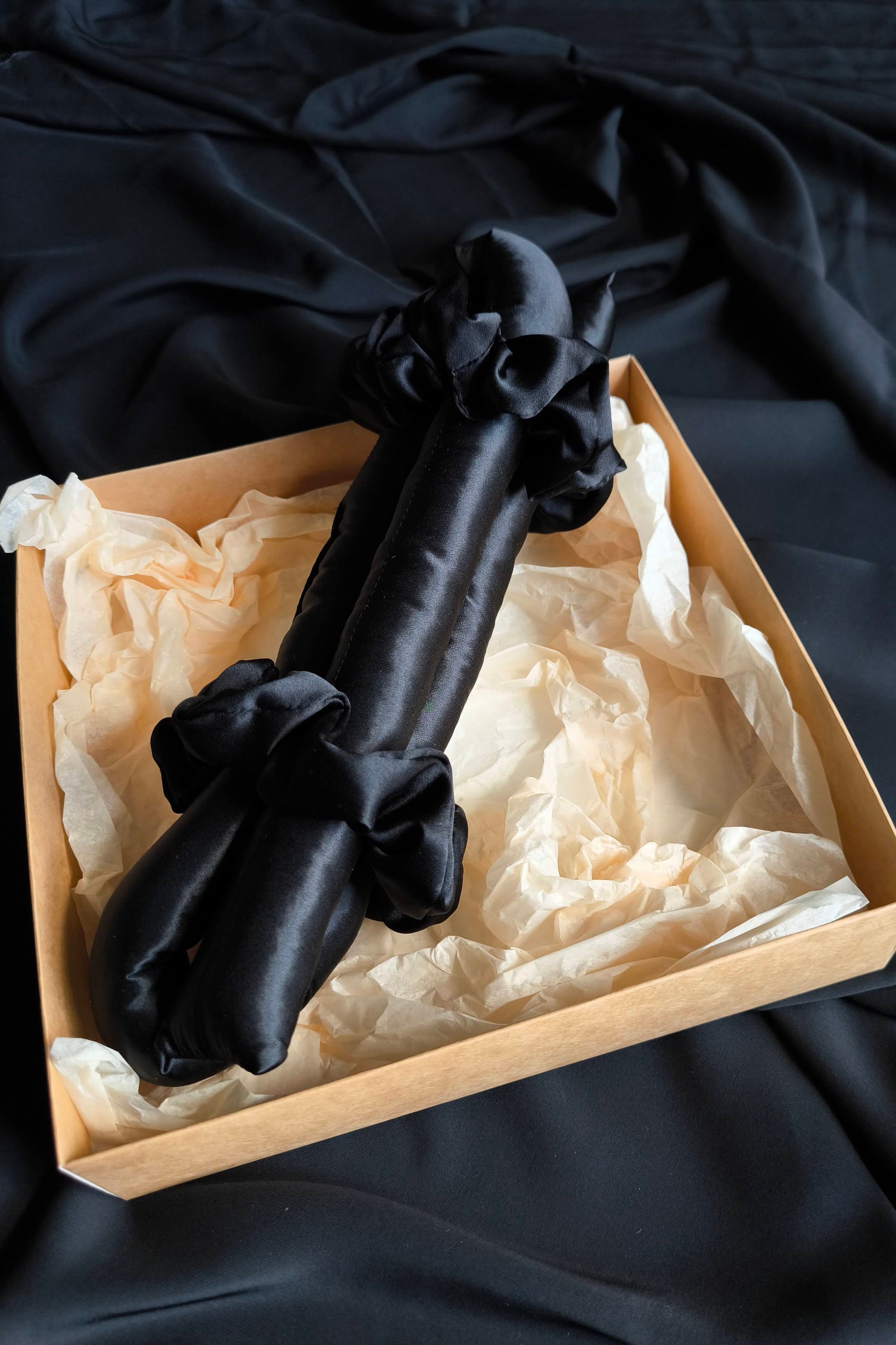 Black heatless hair curler in a box on a dark fabric background