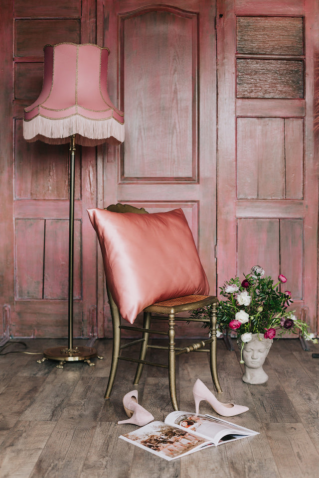 spilvens ar rožu rozā zīda spilvendrānu uz krēsla, sāna skats